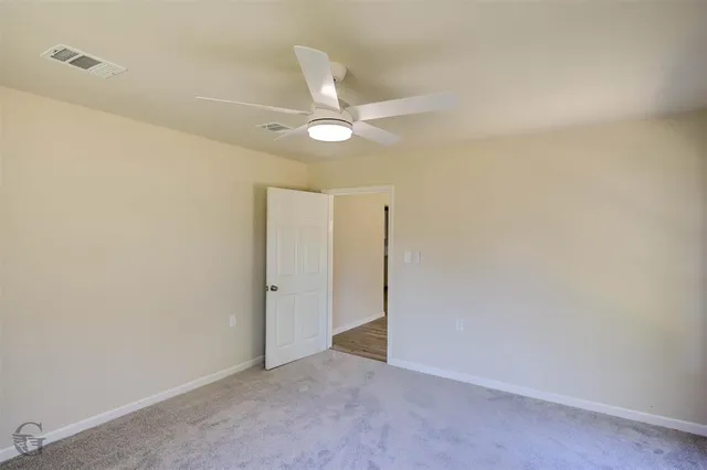 an empty room with closet and a ceiling fan