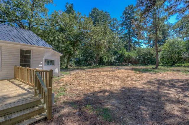 a view of backyard with wooden fence and large trees