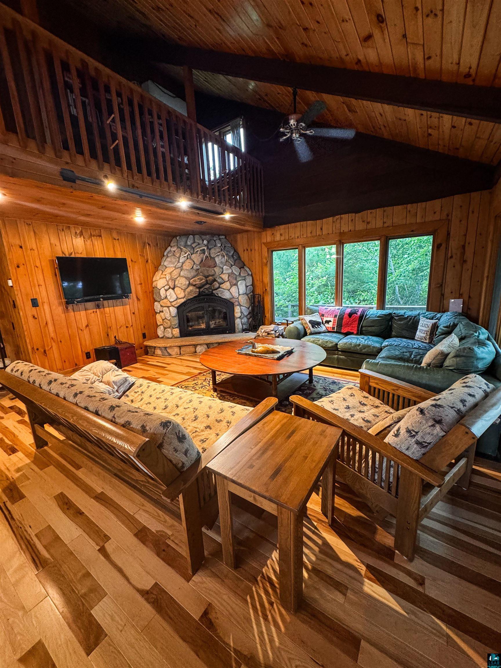 8141 Muskego Point Orr, MN 55771 - Photo 42 of 48 Living area with wooden walls, wood-type flooring, high vaulted ceiling, a wood ceiling with exposed beams, and a ceiling fan