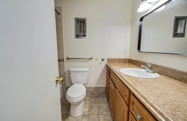 a bathroom with a granite countertop toilet sink and mirror