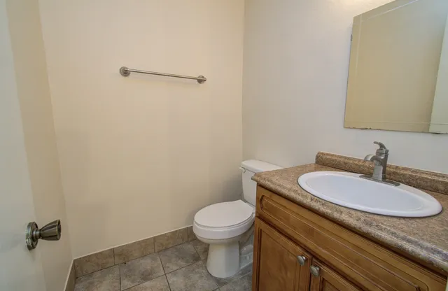 a bathroom with a granite countertop toilet a sink and mirror