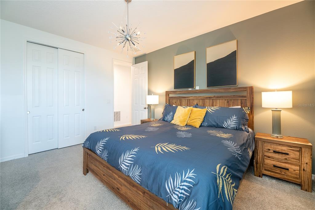 8900 Caroline Bay Court Kissimmee, FL 34747 - Photo 24 of 62 a bed sitting in a bedroom next to a lamp on dresser and a chandelier