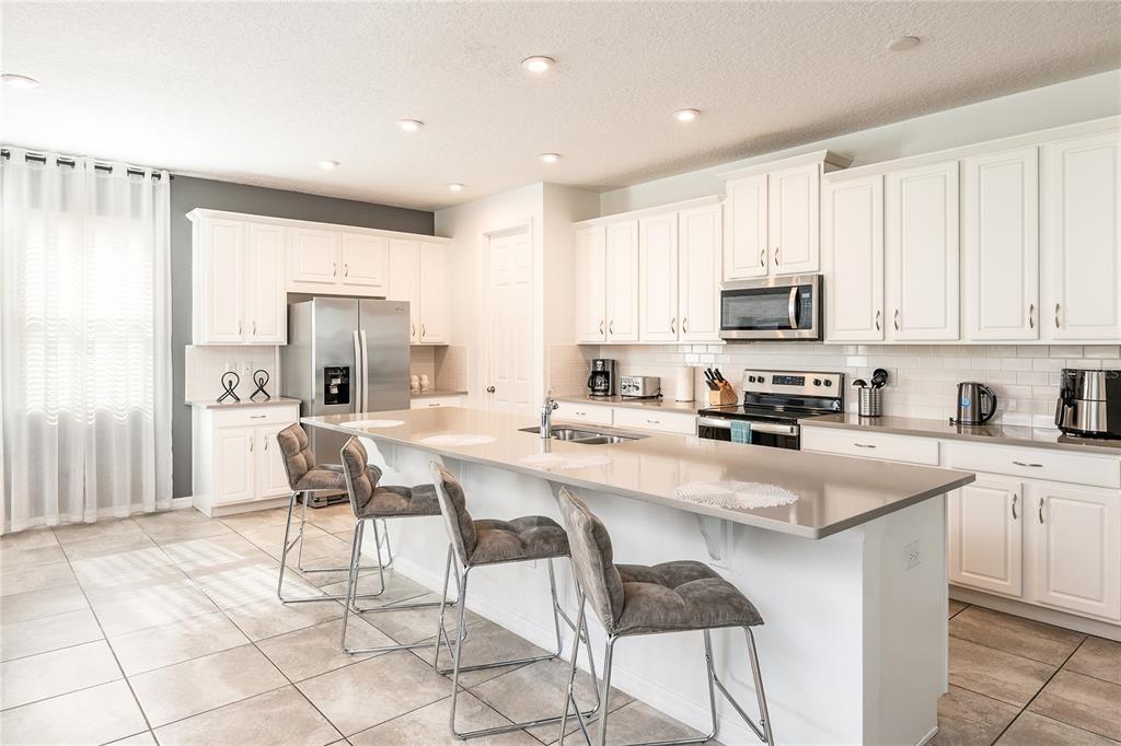 8900 Caroline Bay Court Kissimmee, FL 34747 - Photo 6 of 62 a kitchen with stainless steel appliances a stove a sink a microwave a refrigerator and cabinets