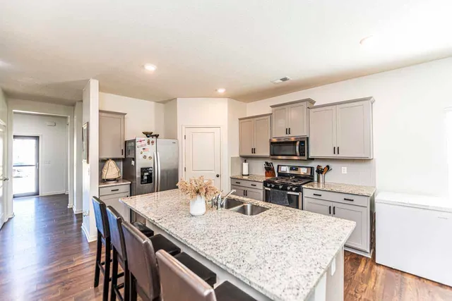 a kitchen with kitchen island granite countertop a sink and refrigerator