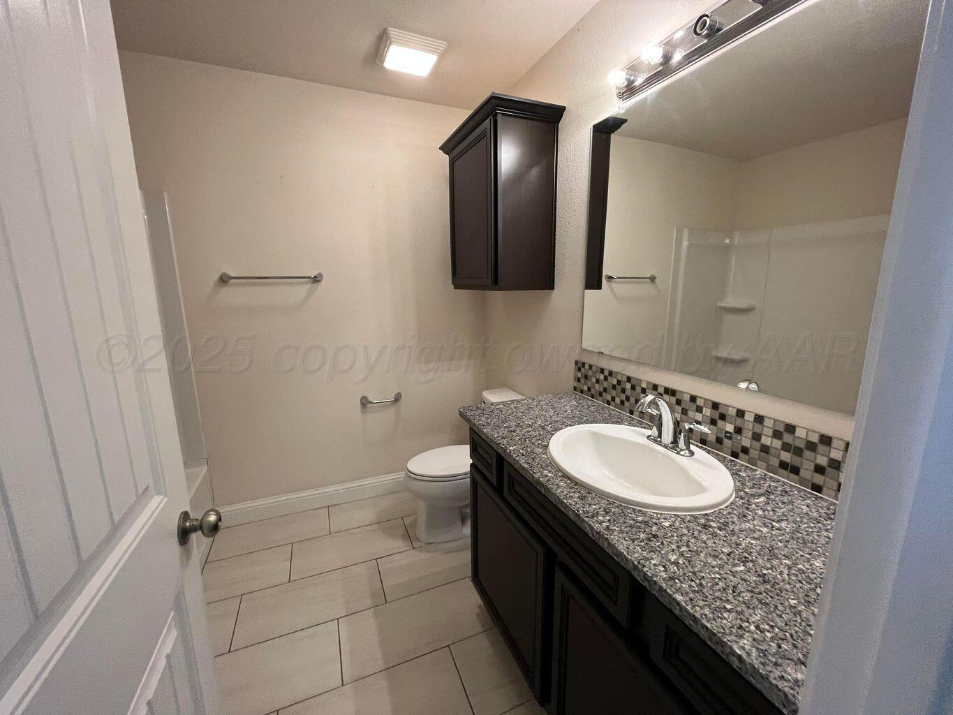 7206 Sinclair Street Amarillo, TX 79119 - Photo 12 of 21 a bathroom with a granite countertop sink toilet and mirror