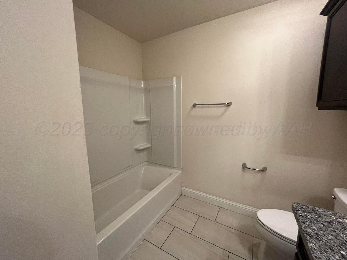 7206 Sinclair Street Amarillo, TX 79119 - Photo 13 of 21 a bathroom with a granite countertop toilet and a bathtub