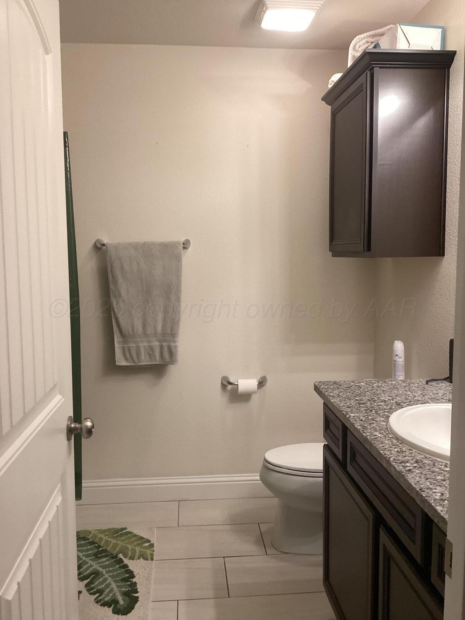 7206 Sinclair Street Amarillo, TX 79119 - Photo 18 of 21 a bathroom with a granite countertop sink a toilet and a mirror