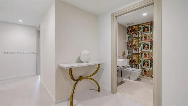 a view of a hallway with a chandelier and a bathroom