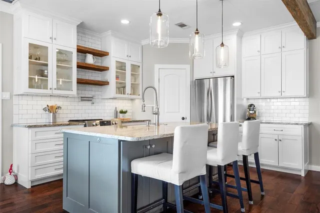 a kitchen with stainless steel appliances granite countertop a dining table chairs sink and cabinets