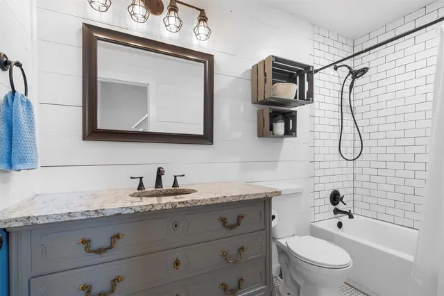 a bathroom with a granite countertop toilet sink and mirror