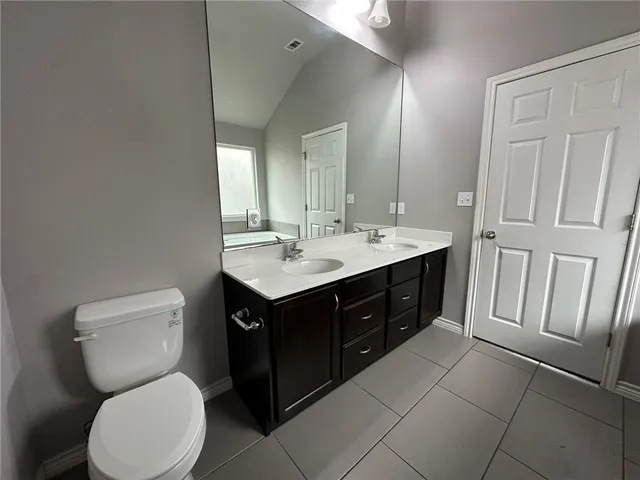 a bathroom with a toilet sink vanity and mirror