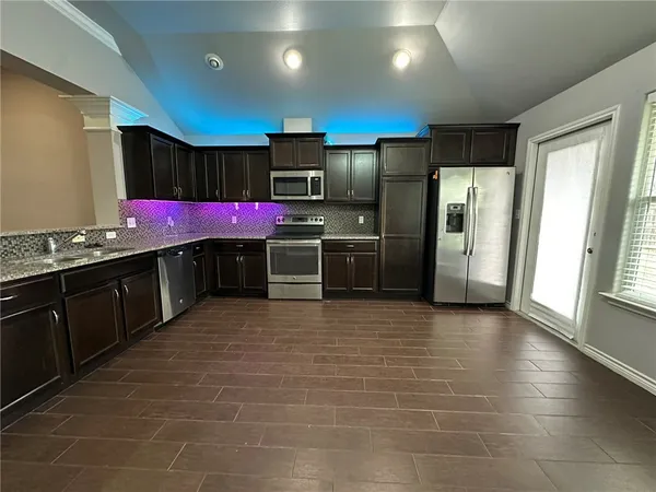 a kitchen with stainless steel appliances a sink a counter top space cabinets and a refrigerator