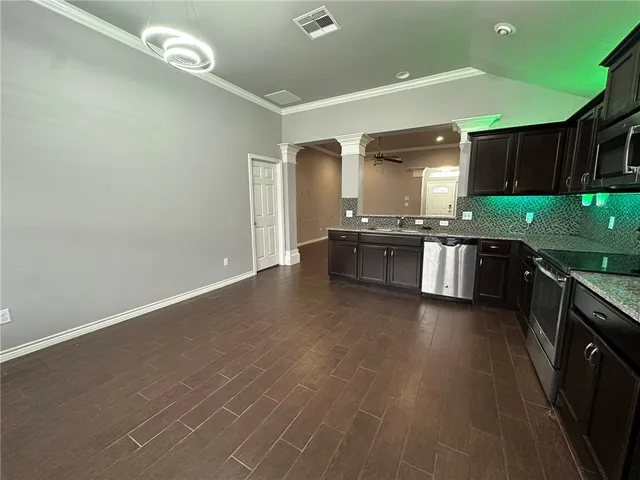 a large kitchen with stainless steel appliances a large counter top a stove a chimney a sink and dishwasher