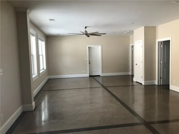 an empty room with windows and ceiling fan