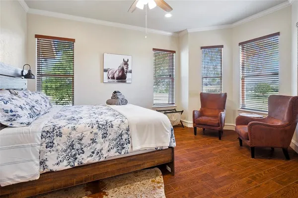 a bedroom with a bed chairs and two windows