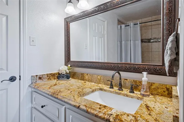 a bathroom with a granite countertop sink and a mirror