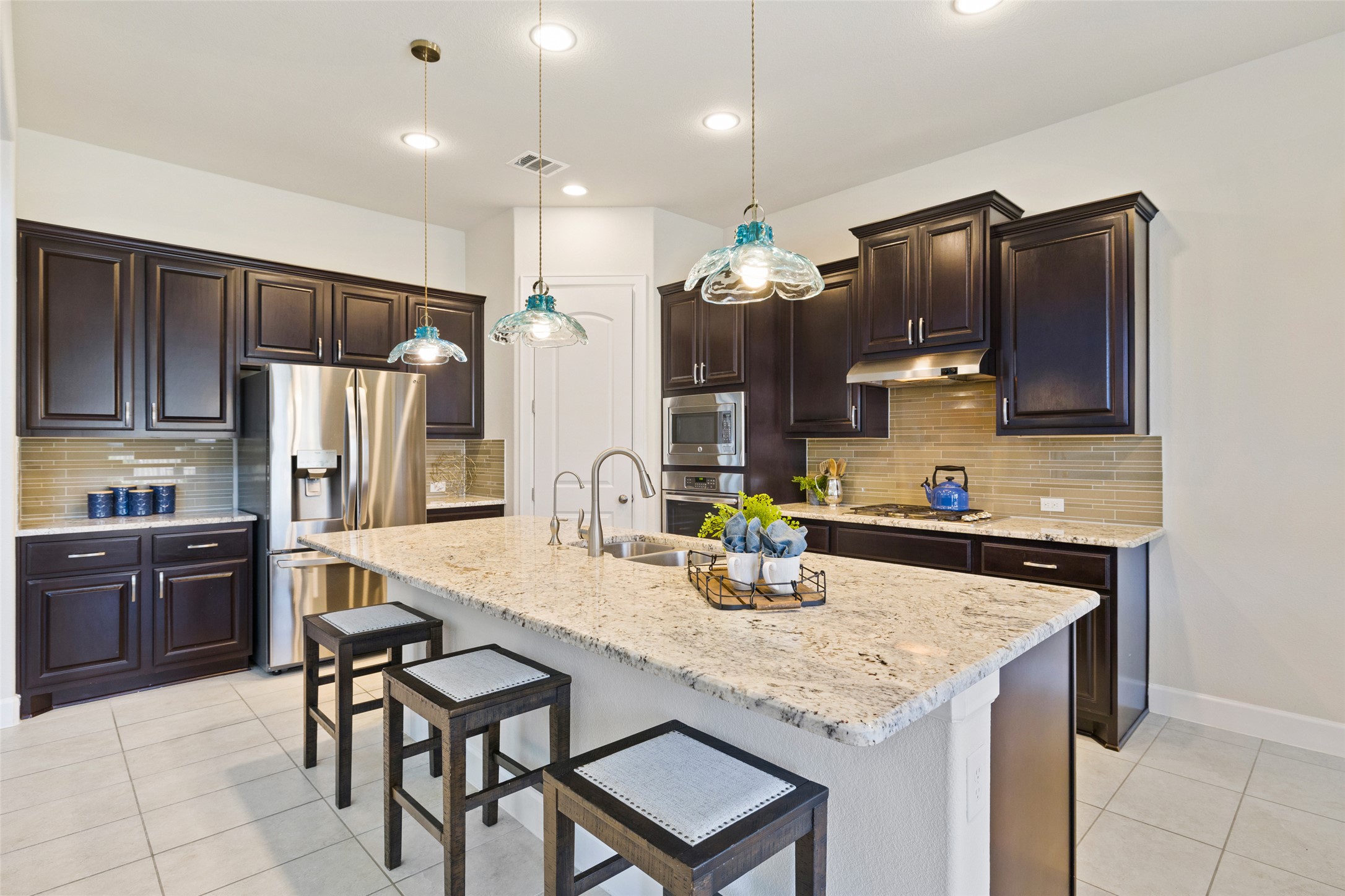 3020 Columbus Loop Round Rock, TX 78665 - Photo 16 of 40 Kitchen featuring a kitchen breakfast bar, dark wood finish cabinetry, stainless steel appliances.