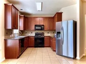 a large kitchen with stainless steel appliances granite countertop a refrigerator and a stove