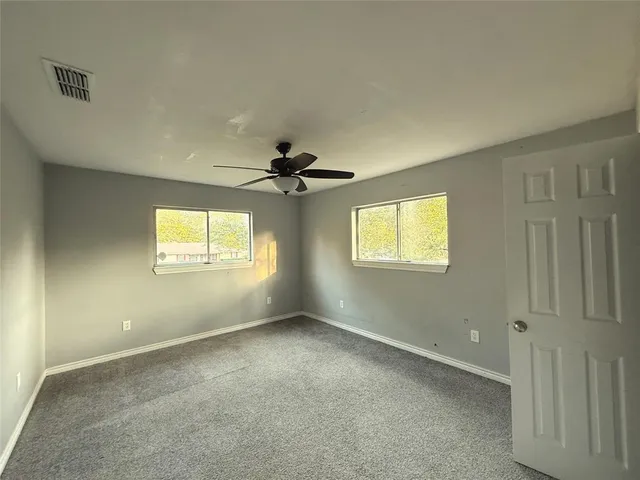 an empty room with windows and fan