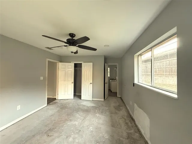a view of n empty room with window and ceiling fan