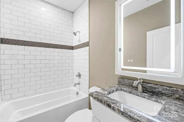 a bathroom with a granite countertop tub sink and mirror