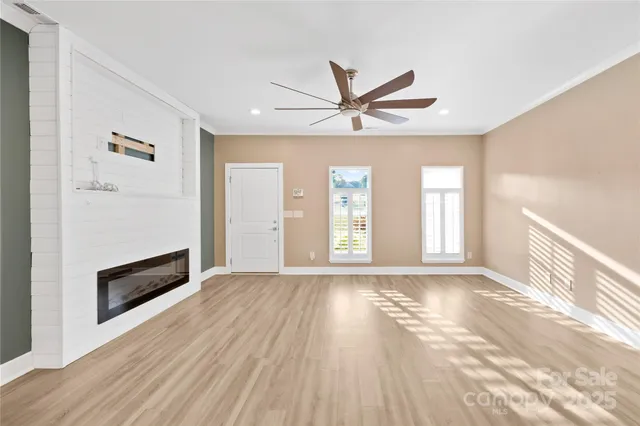 a view of an empty room with a window and wooden floor