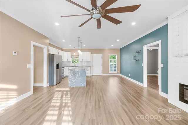 a view of kitchen and empty room with wooden floor