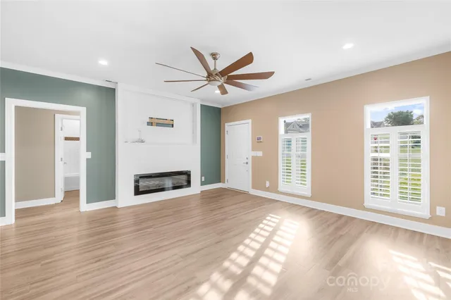a view of an empty room with window and wooden floor