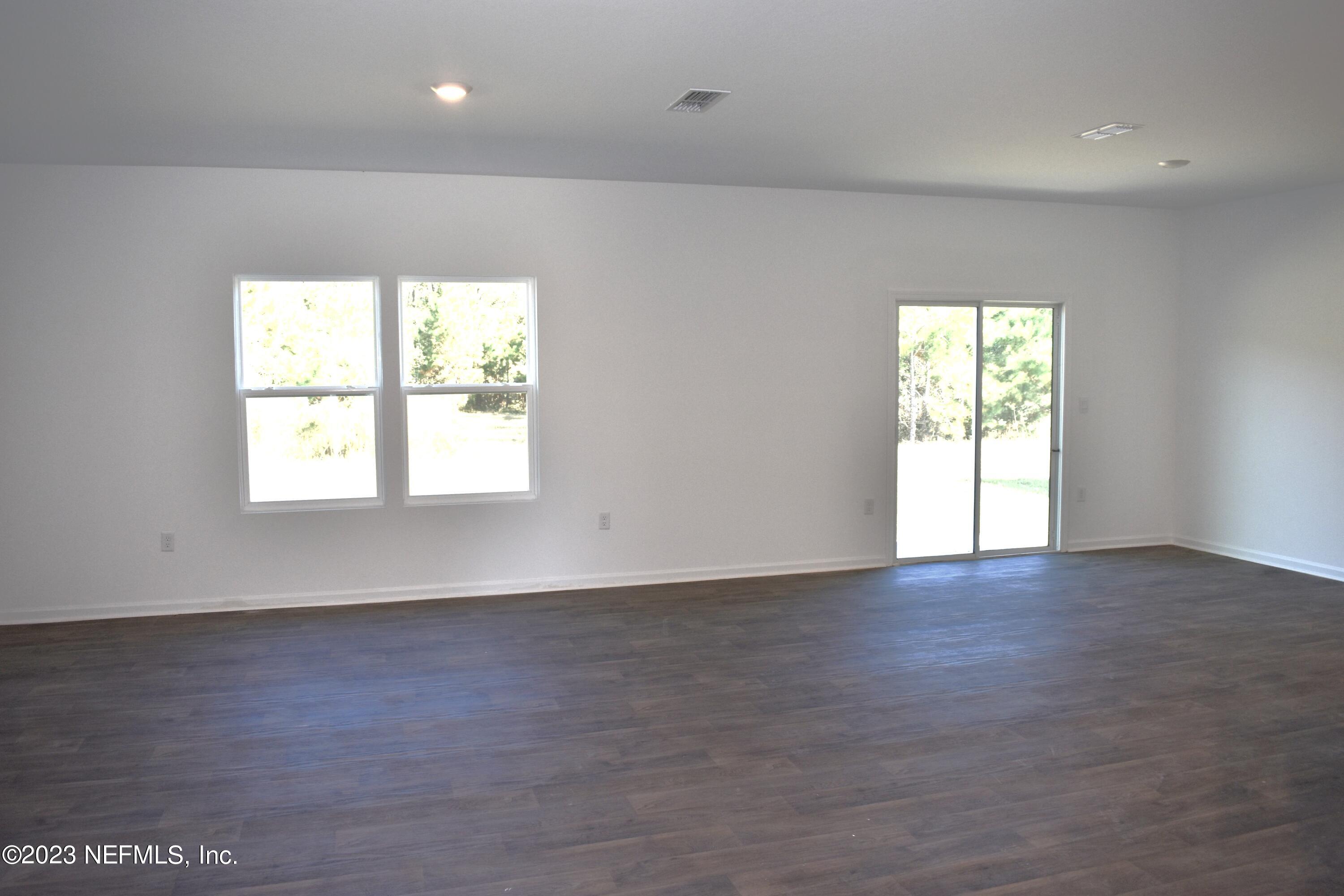 12817 Cacao Tree Trail Jacksonville, FL 32218 - Photo 7 of 41 an empty room with wooden floor and windows