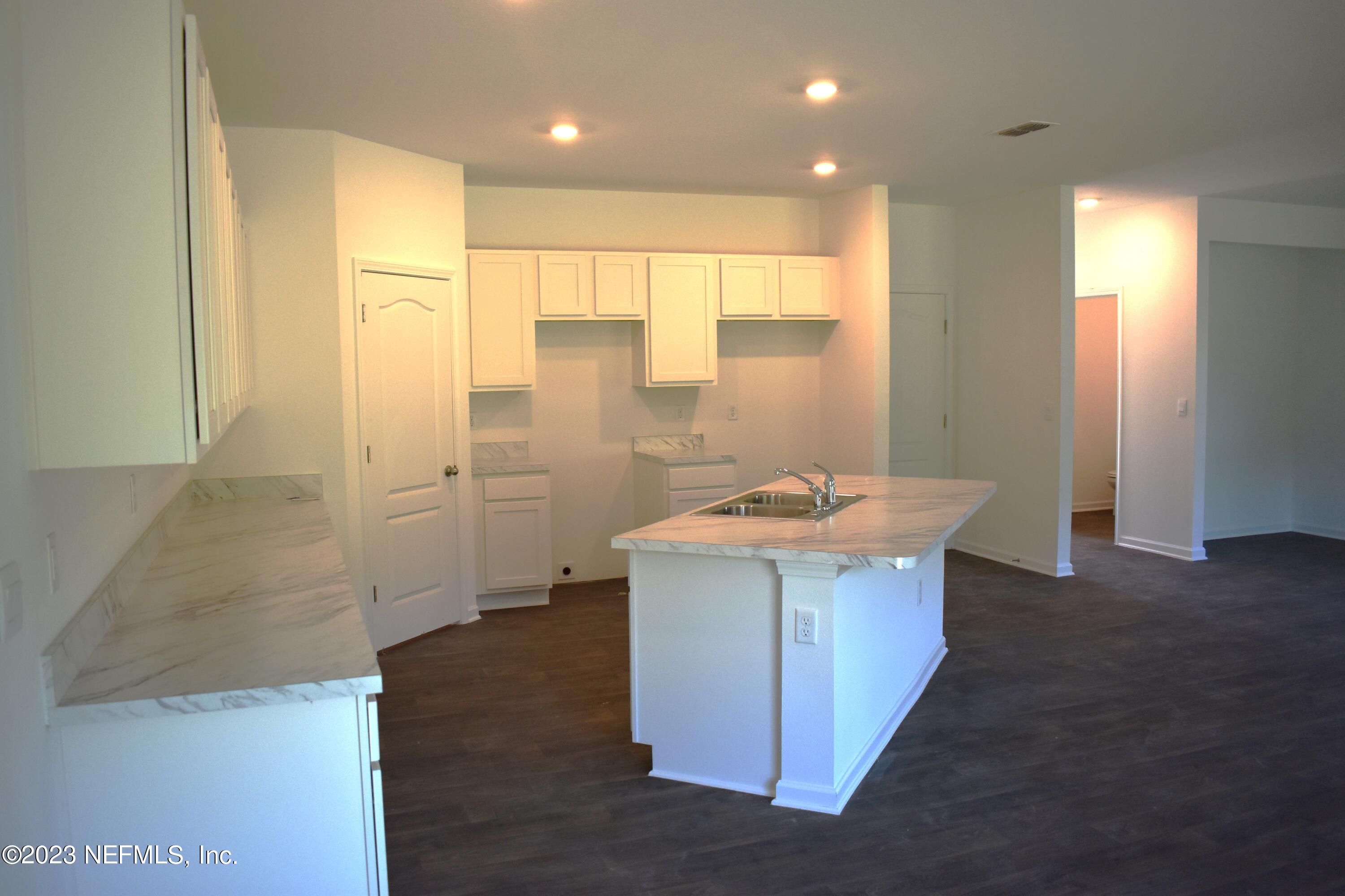 12817 Cacao Tree Trail Jacksonville, FL 32218 - Photo 8 of 41 a utility room with kitchen island a sink a refrigerator and wooden floor
