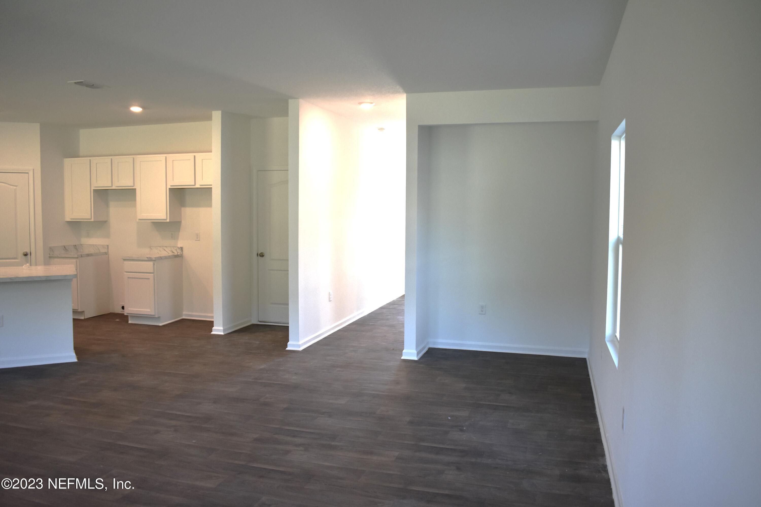 12817 Cacao Tree Trail Jacksonville, FL 32218 - Photo 10 of 41 wooden floor in an empty room with a kitchen
