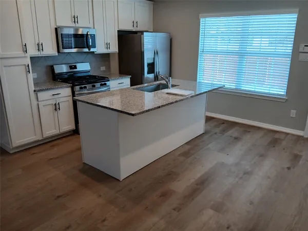 a kitchen with stainless steel appliances granite countertop a stove a refrigerator a sink a microwave and island