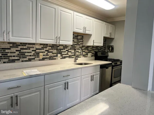 a kitchen with granite countertop white cabinets sink and stainless steel appliances