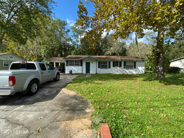 a view of a house with a big yard and large trees