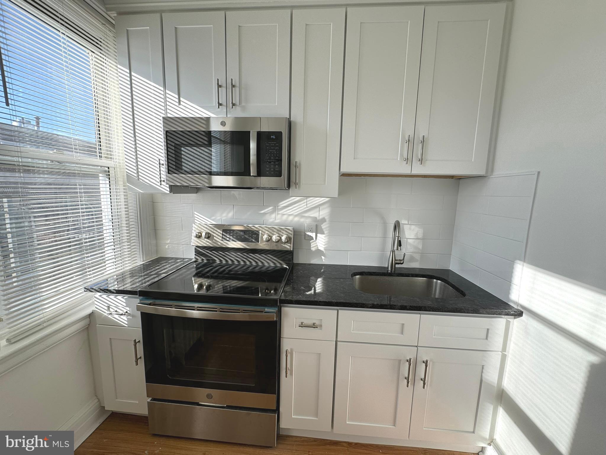 1 North Main Street, Unit 2F Ambler, PA 19002 - Photo 7 of 23 a kitchen with stainless steel appliances granite countertop white cabinets stove top oven and microwave