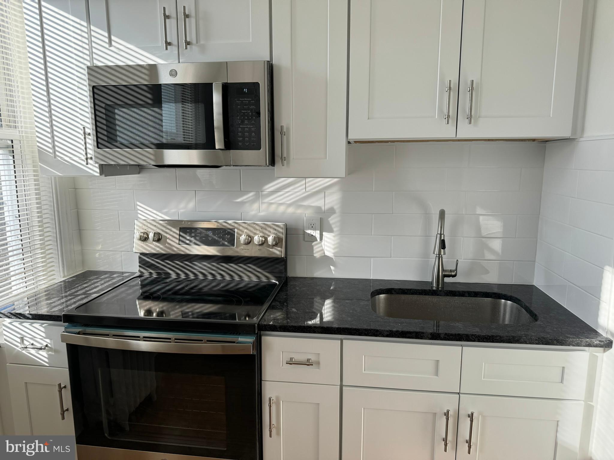 1 North Main Street, Unit 2F Ambler, PA 19002 - Photo 8 of 23 a kitchen with stainless steel appliances granite countertop white cabinets and a stove