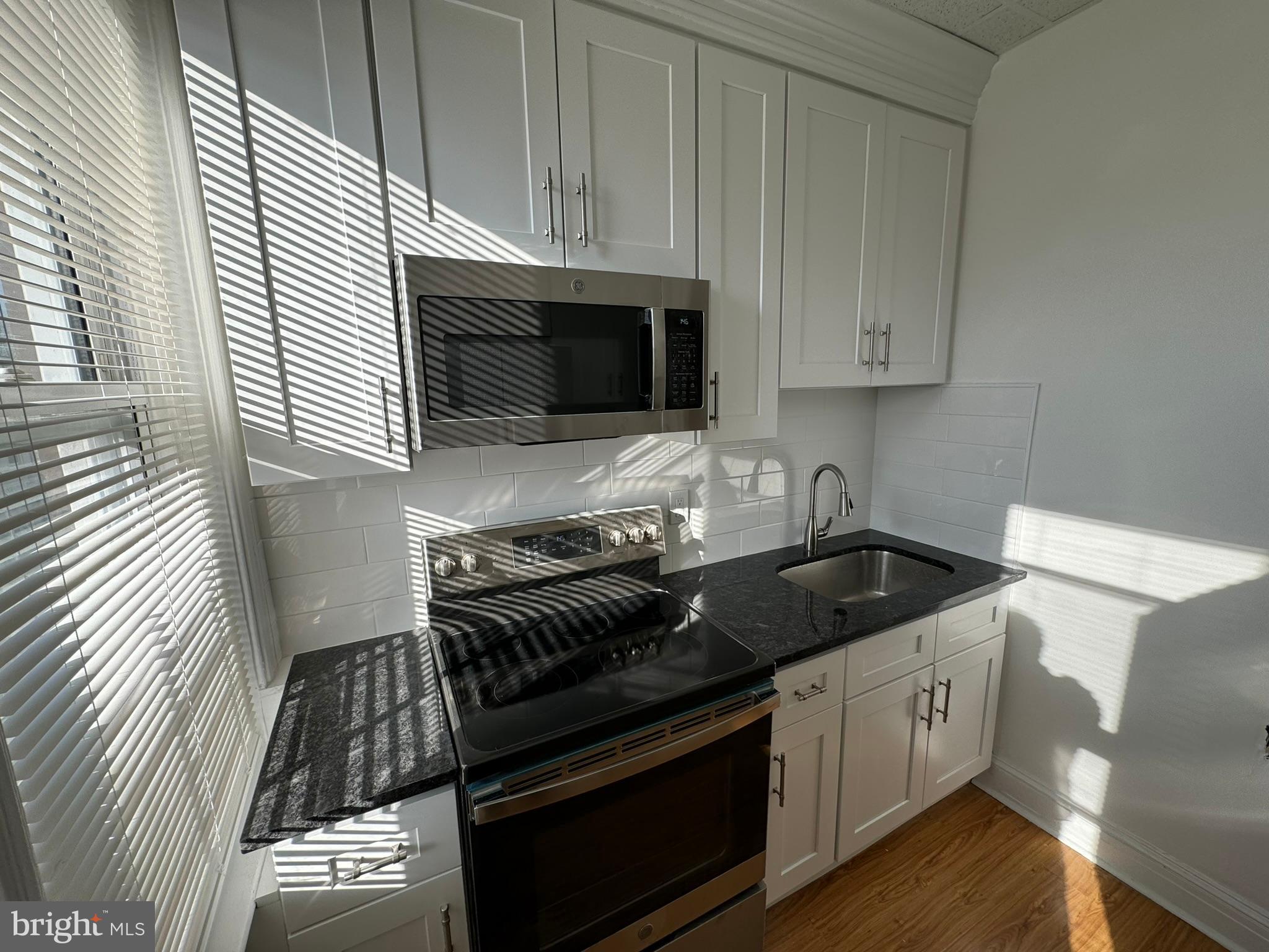 1 North Main Street, Unit 2F Ambler, PA 19002 - Photo 9 of 23 a kitchen with granite countertop white cabinets and black appliances