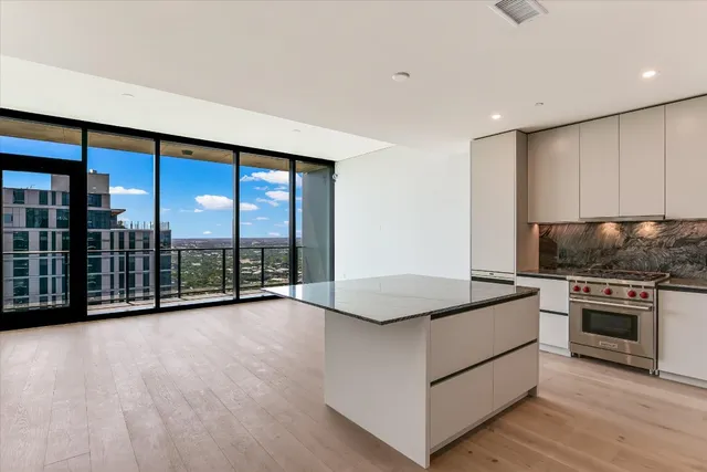 a view of kitchen with granite countertop a stove top oven a sink and dishwasher with wooden floor