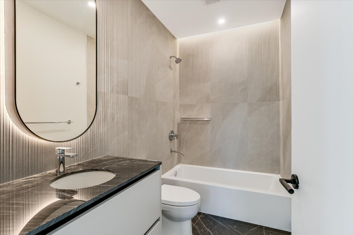 610 Davis Street, Unit 4602 Austin, TX 78701 - Photo 14 of 35 a bathroom with a granite countertop sink toilet and a mirror