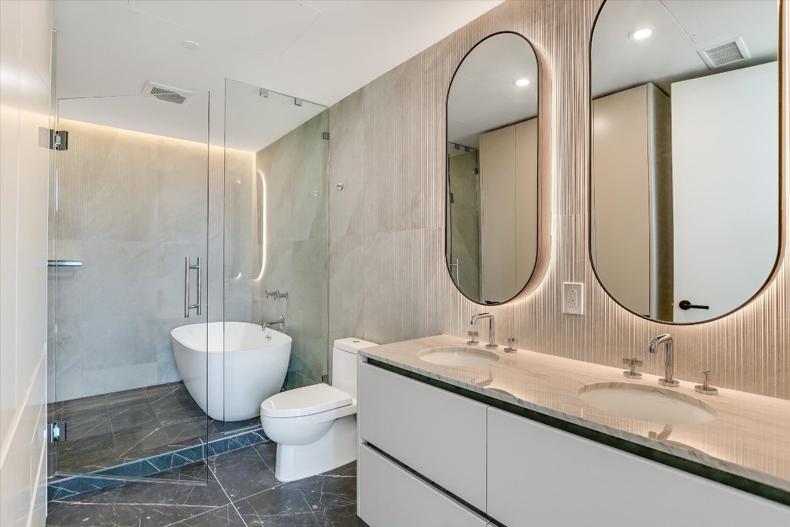 610 Davis Street, Unit 4602 Austin, TX 78701 - Photo 10 of 35 a bathroom with a granite countertop toilet a sink and a mirror