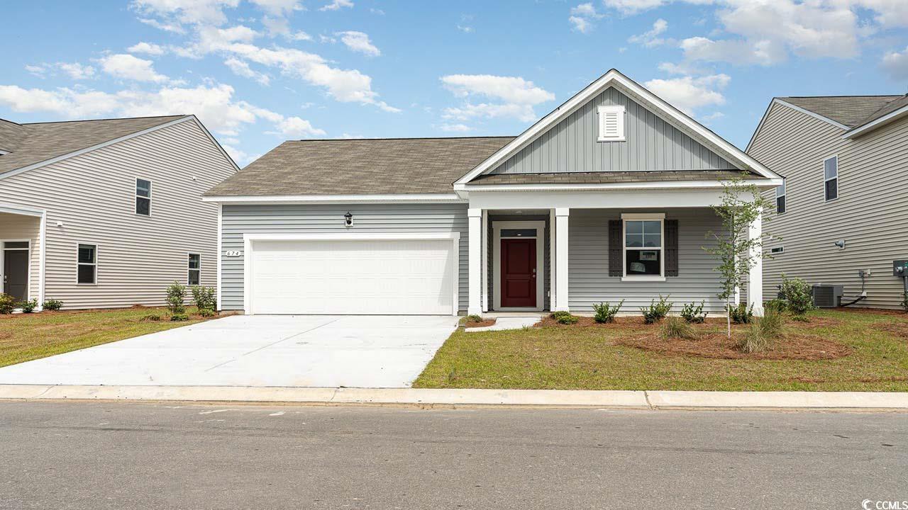 View of front of home with cooling unit, concrete driveway, a front lawn, a garage, and board and batten siding