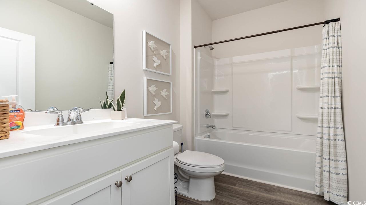 7383 Meadow Walk Loop Loris, SC 29569 - Photo 21 of 29 Full bathroom featuring shower / tub combo with curtain, wood finished floors, vanity, and toilet