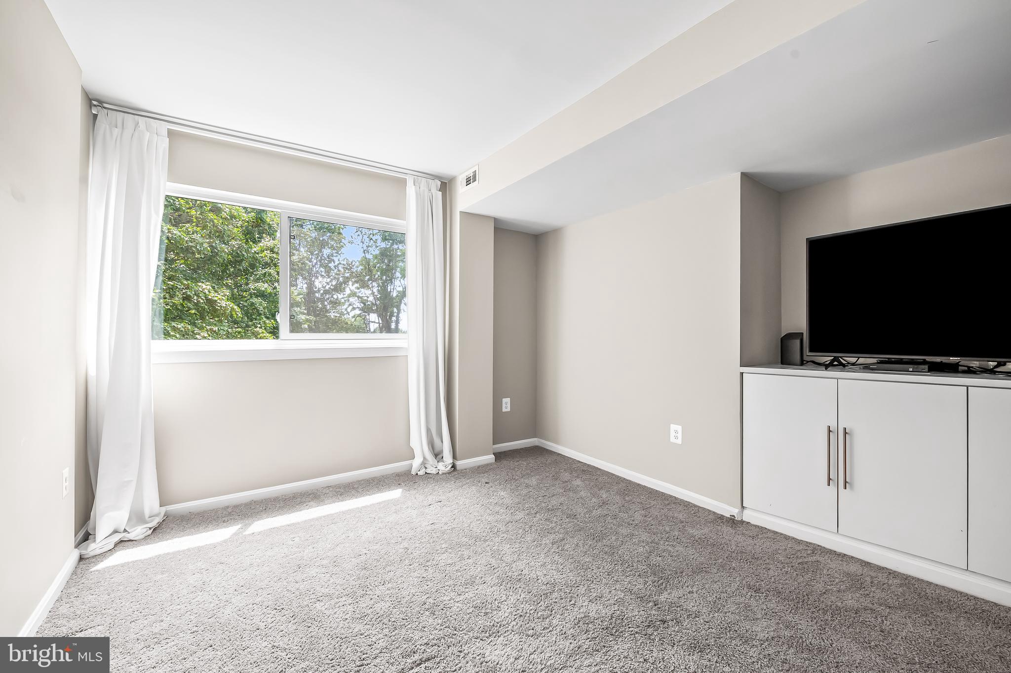 1040 Deer Ridge Drive, Unit 200 Baltimore, MD 21210 - Photo 31 of 38 an empty room with flat screen tv and windows