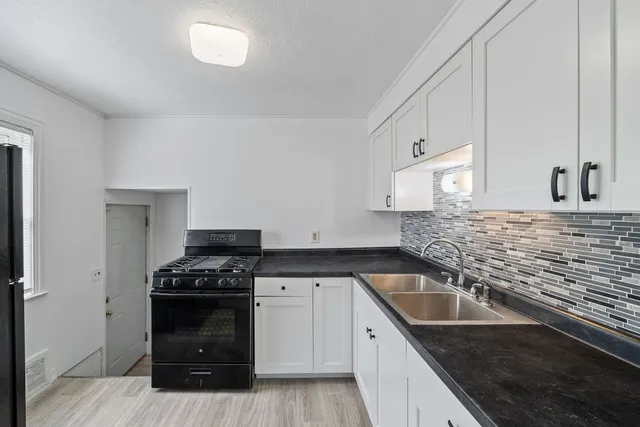 a kitchen with granite countertop stainless steel appliances a sink a stove and cabinets