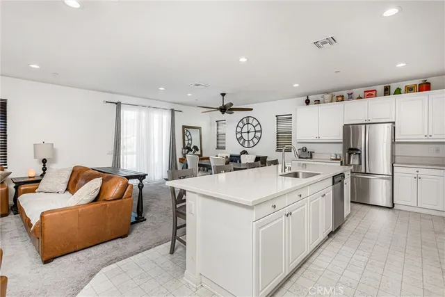 a large white open kitchen with stainless steel appliances kitchen island a stove a refrigerator a couch and a couch