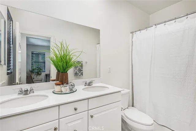 a bathroom with a granite countertop sink a toilet and a mirror