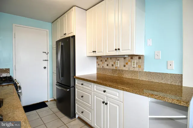 a kitchen with granite countertop a refrigerator and a stove top oven