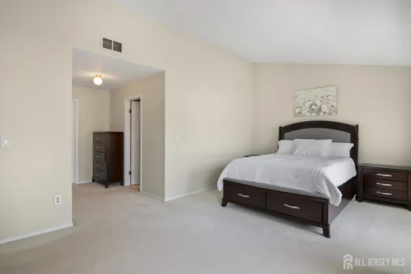 a spacious bedroom with a bed and a lamp