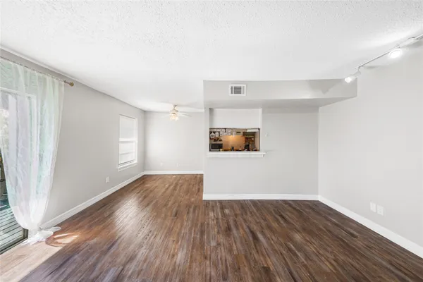 an empty room with wooden floor closet and windows