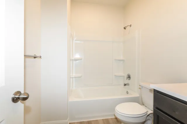 a bathroom with a granite countertop bathtub shower sink vanity and toilet